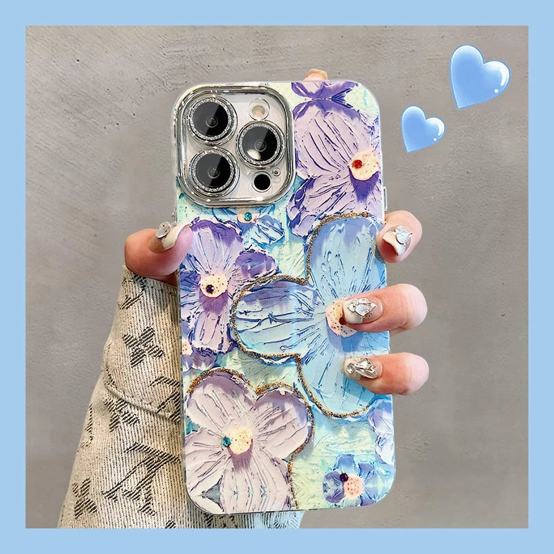 A photo of a phone case with a 3D floral design. The flowers are painted in pastel colors and adorned with glitter and rhinestones. The case is being held in someone's hand.