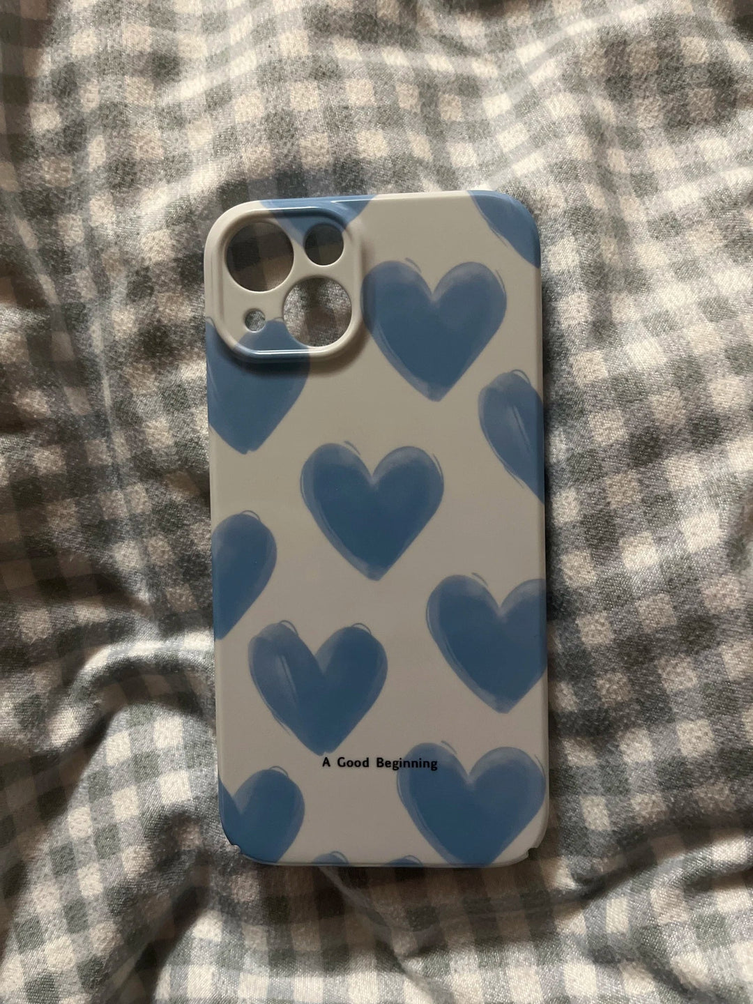 Couple Hearts for iPhone - Acrylic features playful heart patterns in blue and the words “A Good Beginning” at the bottom, set against a checkered fabric background.