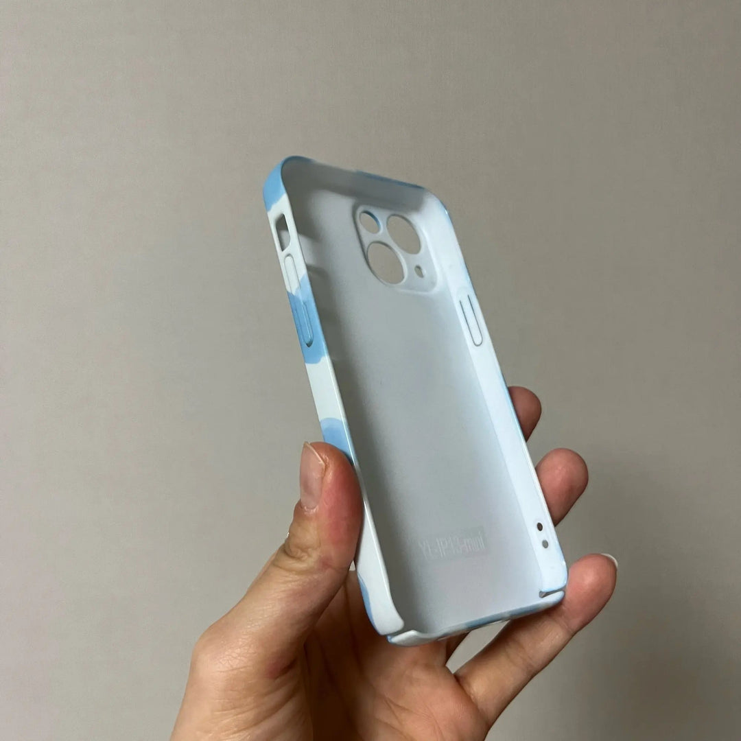 A hand holding the "Couple Hearts for iPhone - Acrylic" case, designed in white and light blue with multiple cutouts for buttons and cameras, featuring playful heart patterns against a plain background.