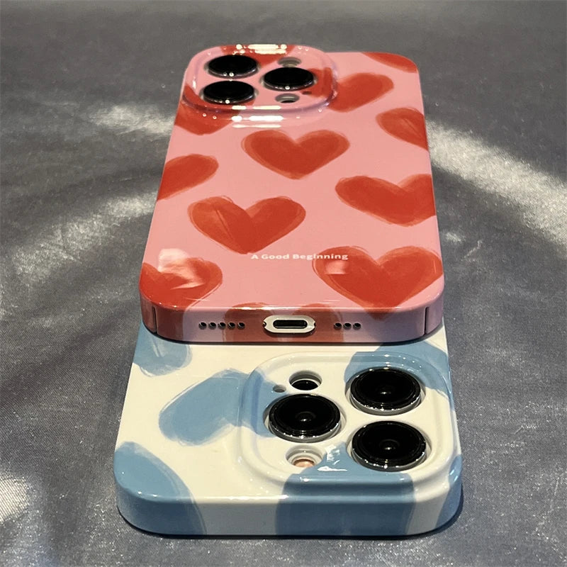 Two iPhones adorned with Couple Hearts for iPhone - Acrylic cases: one featuring a pink design with red hearts and the other a white design with blue hearts. Both phones come in slim cases and sport triple camera setups, effortlessly merging style with functionality.