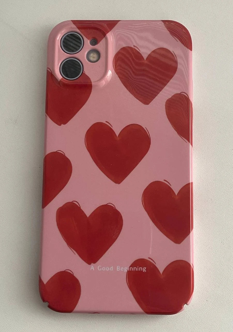 The Couple Hearts for iPhone case boasts a playful design with red heart patterns on a pink background and the text "A Good Beginning" at the bottom, delivering both charm and protection through its stylish slim acrylic construction.