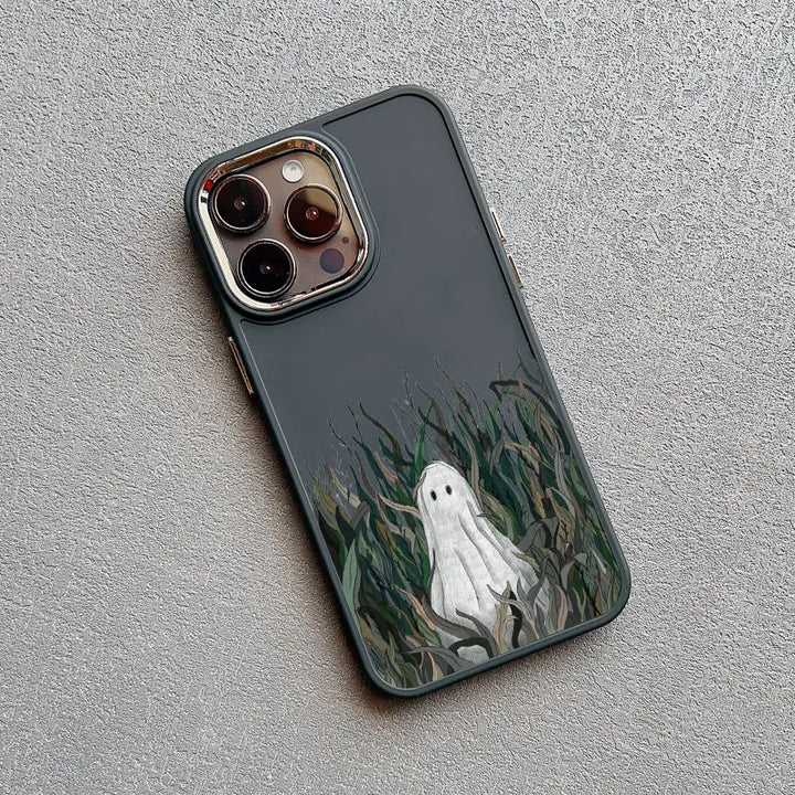 A dark gray phone case with a white ghost illustration sitting in tall grass. The ghost has large, round eyes and a small, curved mouth.