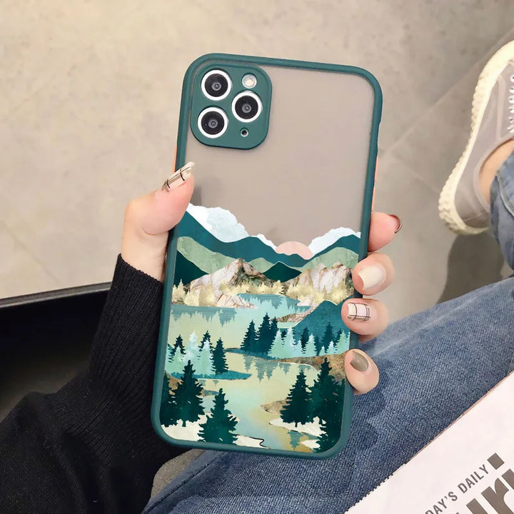 A green phone case with a frosted back showing a serene landscape with mountains, a lake, and a forest