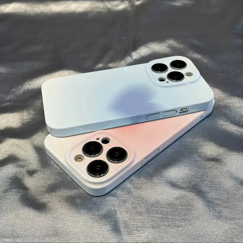 Two Hearts for iPhone cases, one in light blue and the other in pink, are displayed on a reflective surface, highlighting the smartphones' triple rear cameras.