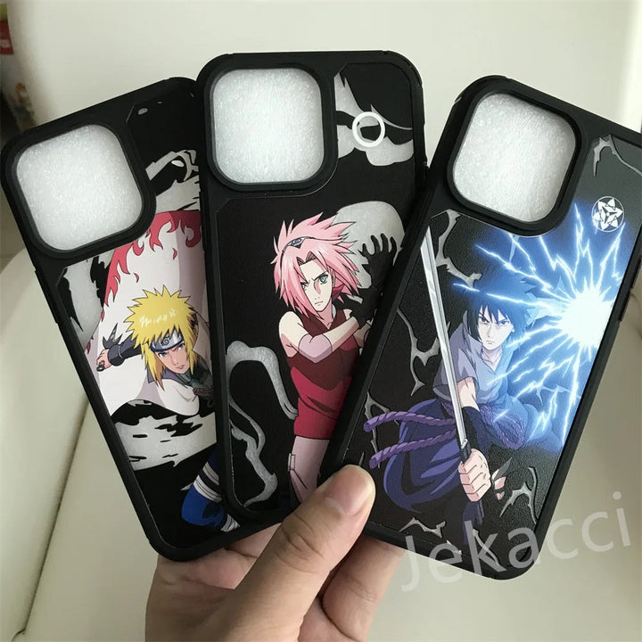 A hand holding three Hidden Leaf Legends for iPhone cases featuring anime characters in action poses: one with Naruto, the blonde-haired character; one with a pink-haired character; and one with Sasuke, the dark-haired character wielding lightning.