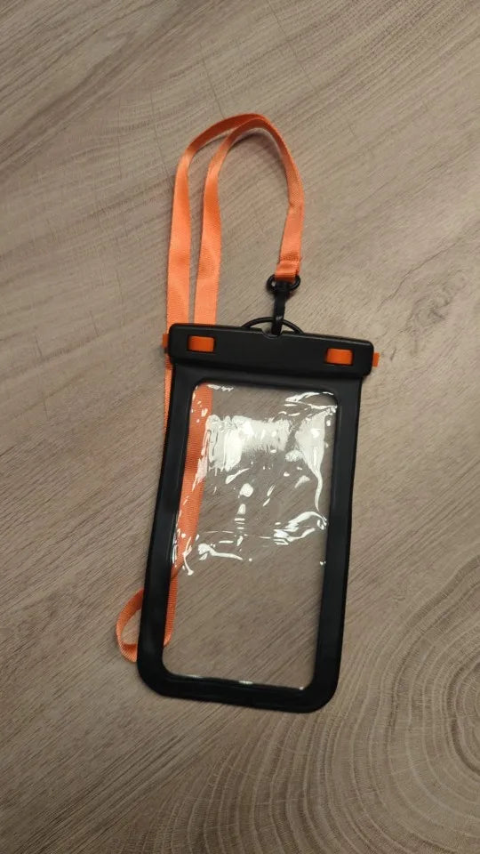 An IPX8 Waterproof Phone Pouch with a clear plastic design and an orange strap, perfect for outdoor activities, lies on a wooden surface.