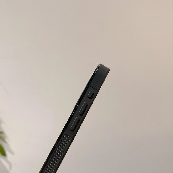 A close-up image of the Itachi Angle Art smartphone's side profile, showcasing volume control buttons and a textured grip detail with an Itachi-themed design. The blurred background with minimal detail highlights its sleek, MagSafe-compatible build.