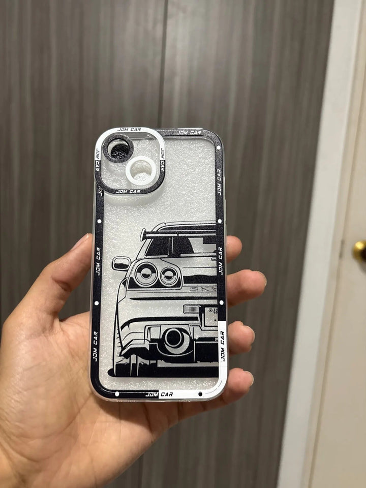 A hand holds a smartphone encased in the JDM Clear for iPhone, featuring a black and white illustration of a JDM car's rear view.