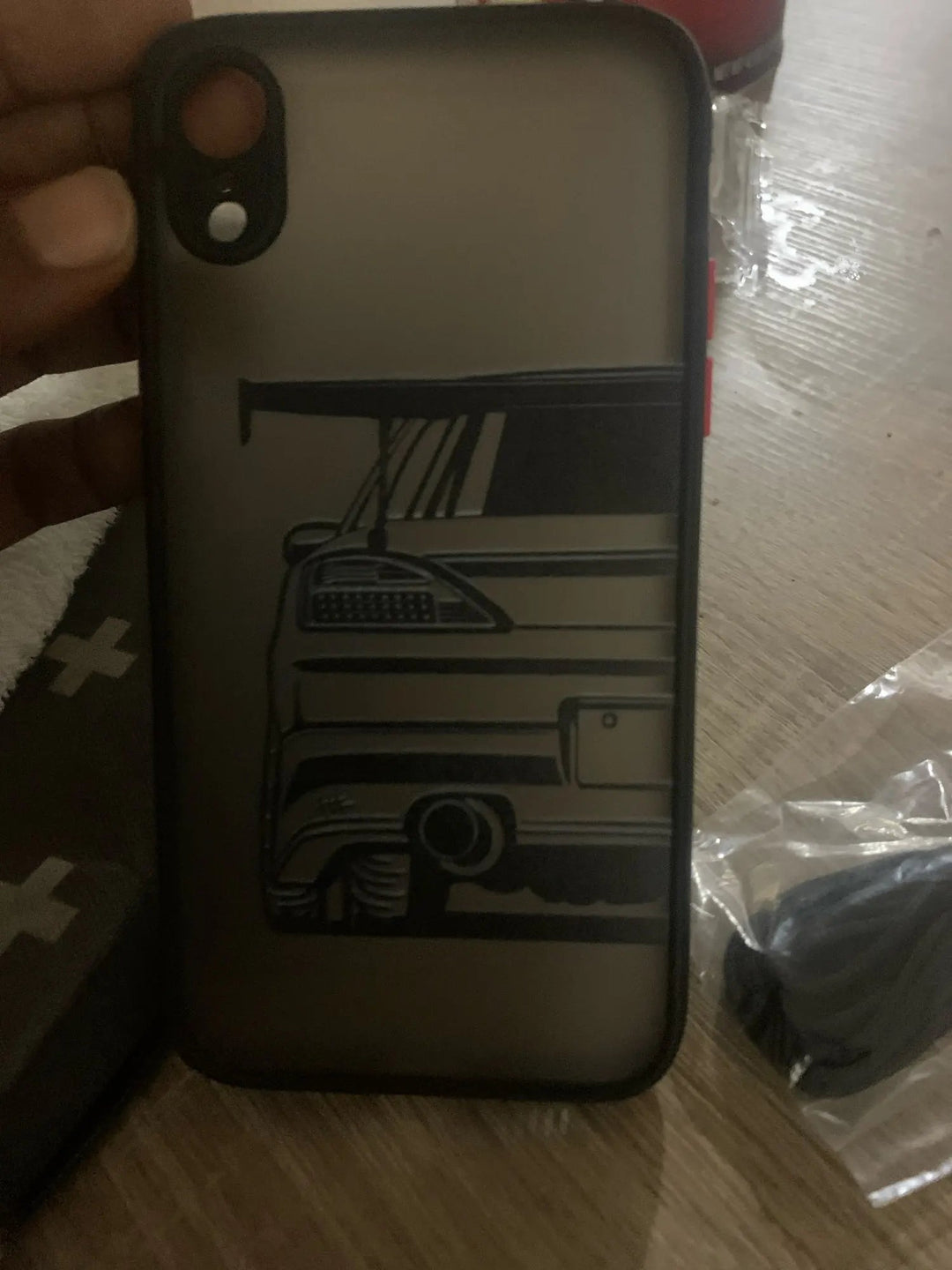 A person holding the JDM Frosted for iPhone TPU phone case, which has a matte finish and features an illustration of a car's rear end complete with a spoiler, taillight, and exhaust.