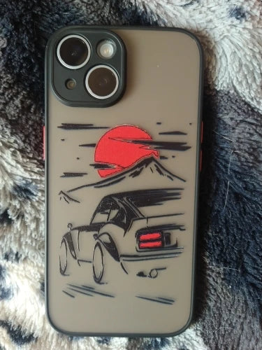 The JDM Sunset for iPhone is a protective smartphone case showcasing a stylized drawing of a JDM car, a mountain, and a red sun.