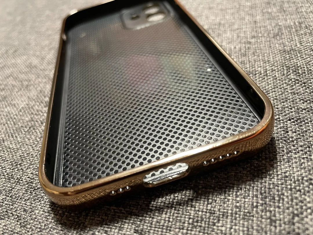 A close-up of the Lambskin Leather for iPhone, with its textured interior, resting on a gray fabric surface and showcasing its gold camera cutout.