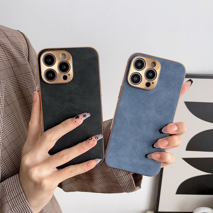 Two hands holding smartphones protected by premium Lambskin Leather cases in elegant black and sapphire blue hues. The individual, showcasing long, decorated nails and donning a plaid jacket, stands against a backdrop of abstract art.