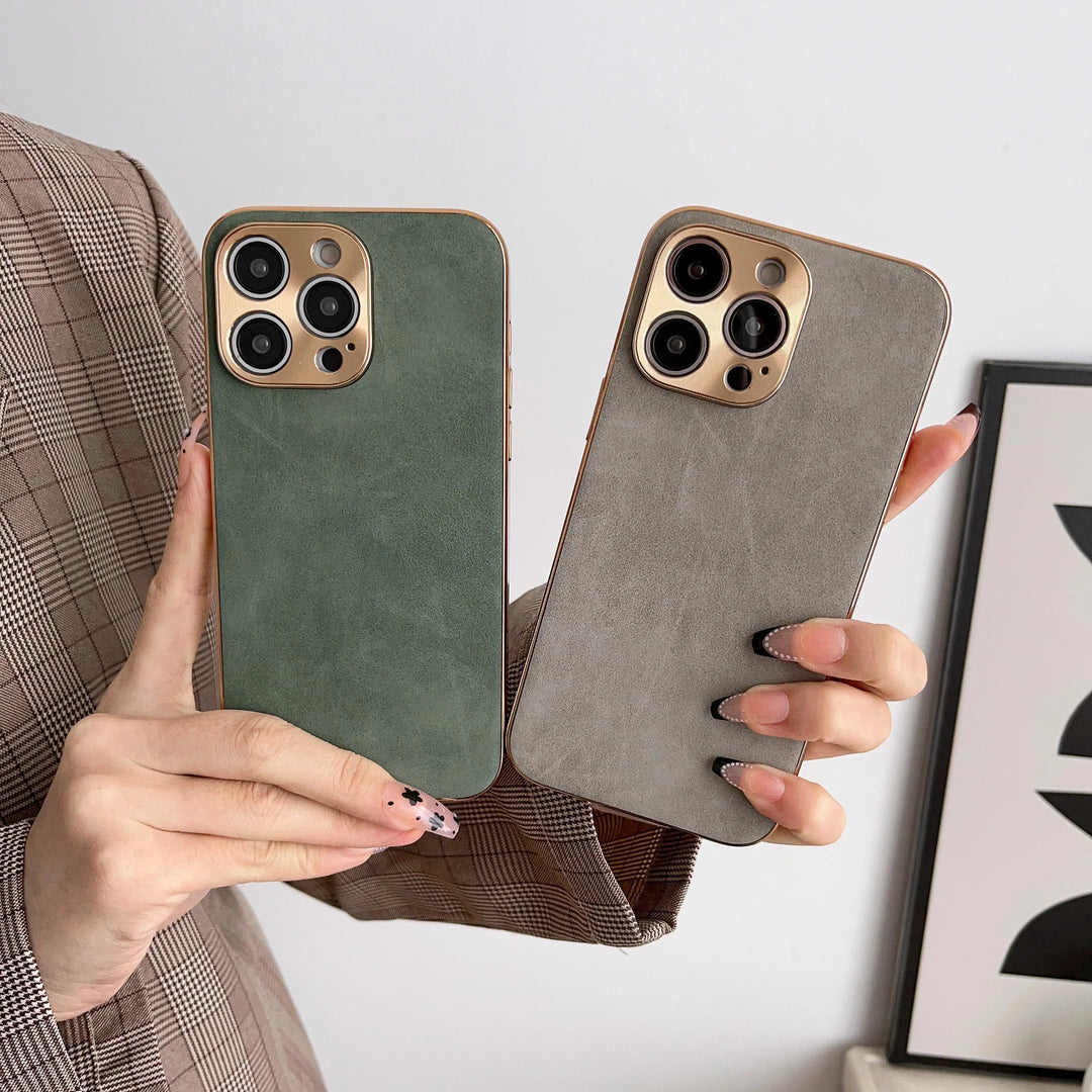 Two hands holding smartphones in premium green and gray Lambskin Leather for iPhone cases with gold camera cutouts, featuring multiple lenses. The person is wearing a plaid jacket.