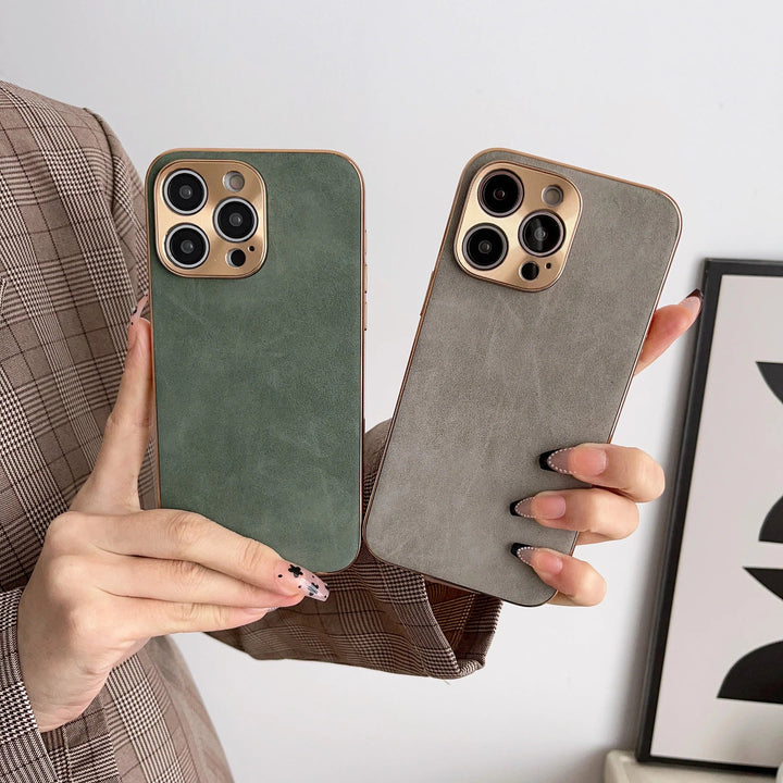 Two hands holding smartphones in premium green and gray Lambskin Leather for iPhone cases with gold camera cutouts, featuring multiple lenses. The person is wearing a plaid jacket.