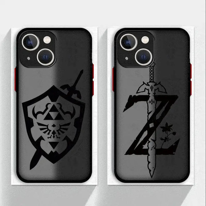 Two black iPhone cases from the Legend of Zelda collection are shown. The left case features a design with a sword and a Hylian shield that has a crest with wings and triangles. The right case displays a stylized 'Z' with the Master Sword through it and a small emblem at the bottom right, inspired by Legend of Zelda.