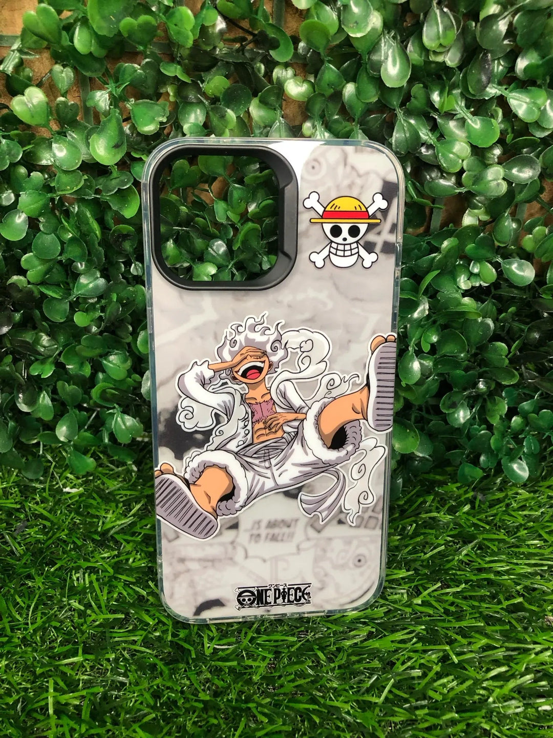 Luffy Gear 5 for iPhone Phone Case featuring a character from One Piece with a skull logo, displayed on green artificial grass, offering anti-scratch protection.