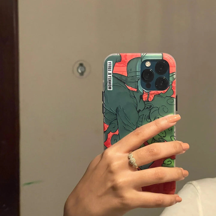 A hand with a ring holds a smartphone adorned with a Luffy Gradient for iPhone case, reflecting in a mirror.