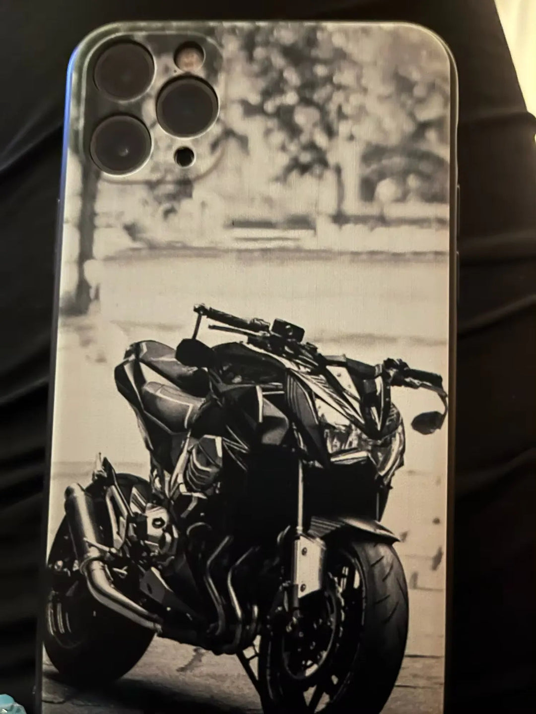 Introducing the Motocross for iPhone: a sleek phone case featuring a black and white image of a motorcycle, with camera lenses visible at the top left corner. This lightweight case provides excellent anti-scratch protection for your device.