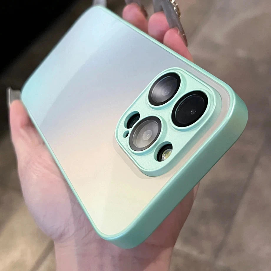 A person holds an iPhone encased in an Ombre Glass Case, showcasing the teal green back with its three cameras and flash, emphasizing the phone's anti-scratch design.