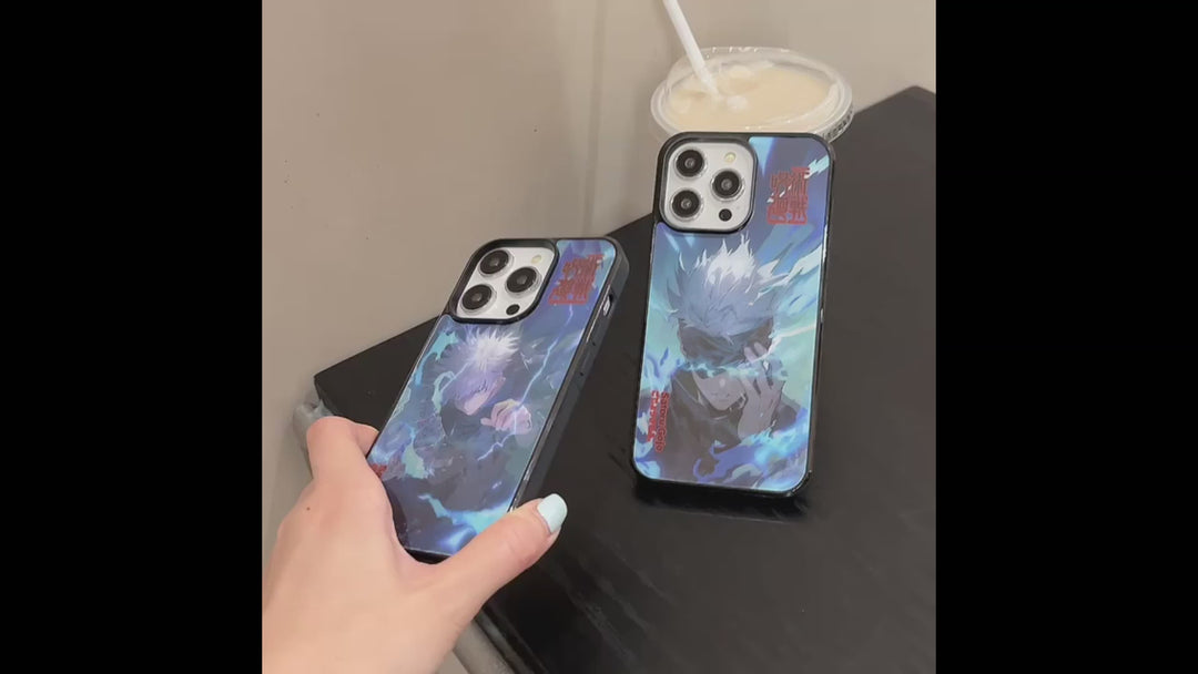 Video of two phone cases featuring Satoru Gojo from Jujutsu Kaisen. The cases have a black frame with a holographic effect, showcasing Gojo's intense expression and lightning-like energy.