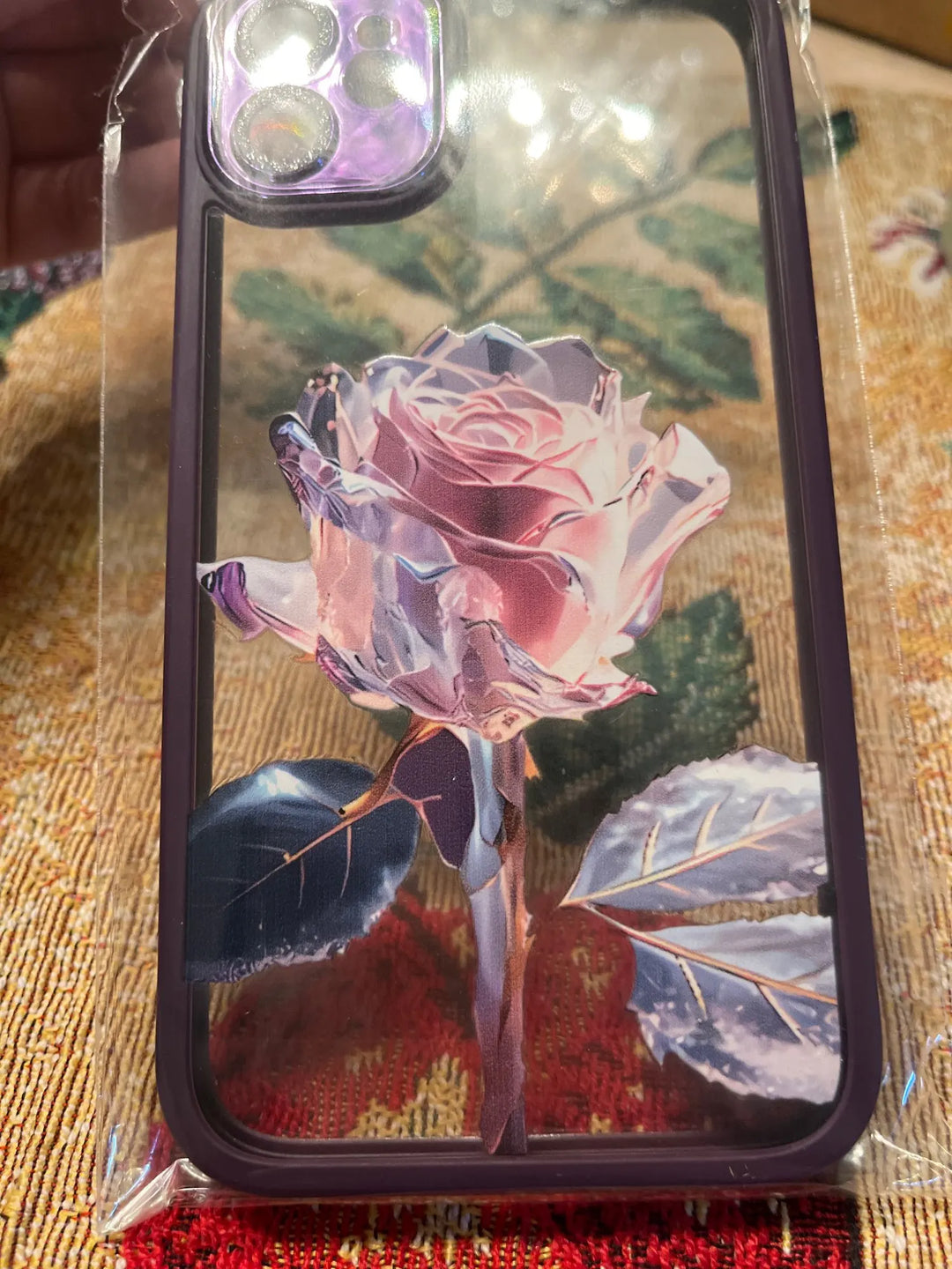 A phone case with a clear, transparent back featuring a vibrant rose design