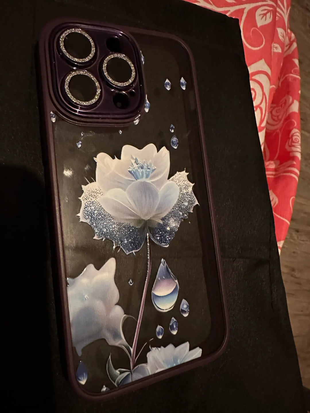 A phone case with a clear, transparent back featuring a vibrant rose design