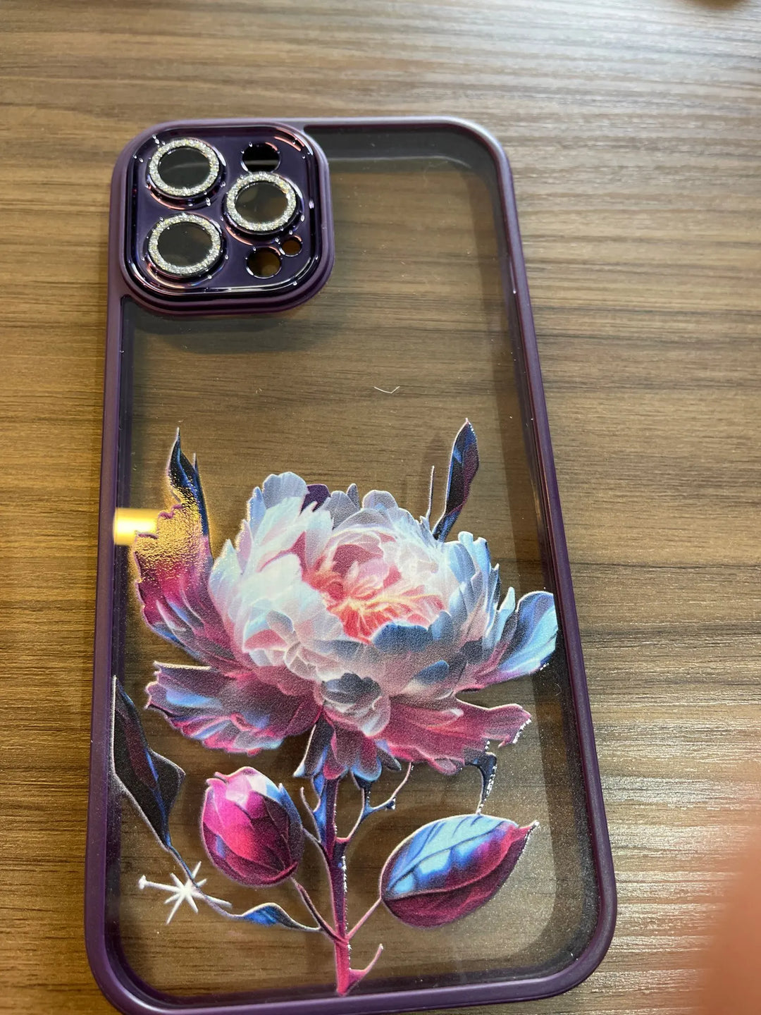 A phone case with a clear, transparent back featuring a vibrant rose design