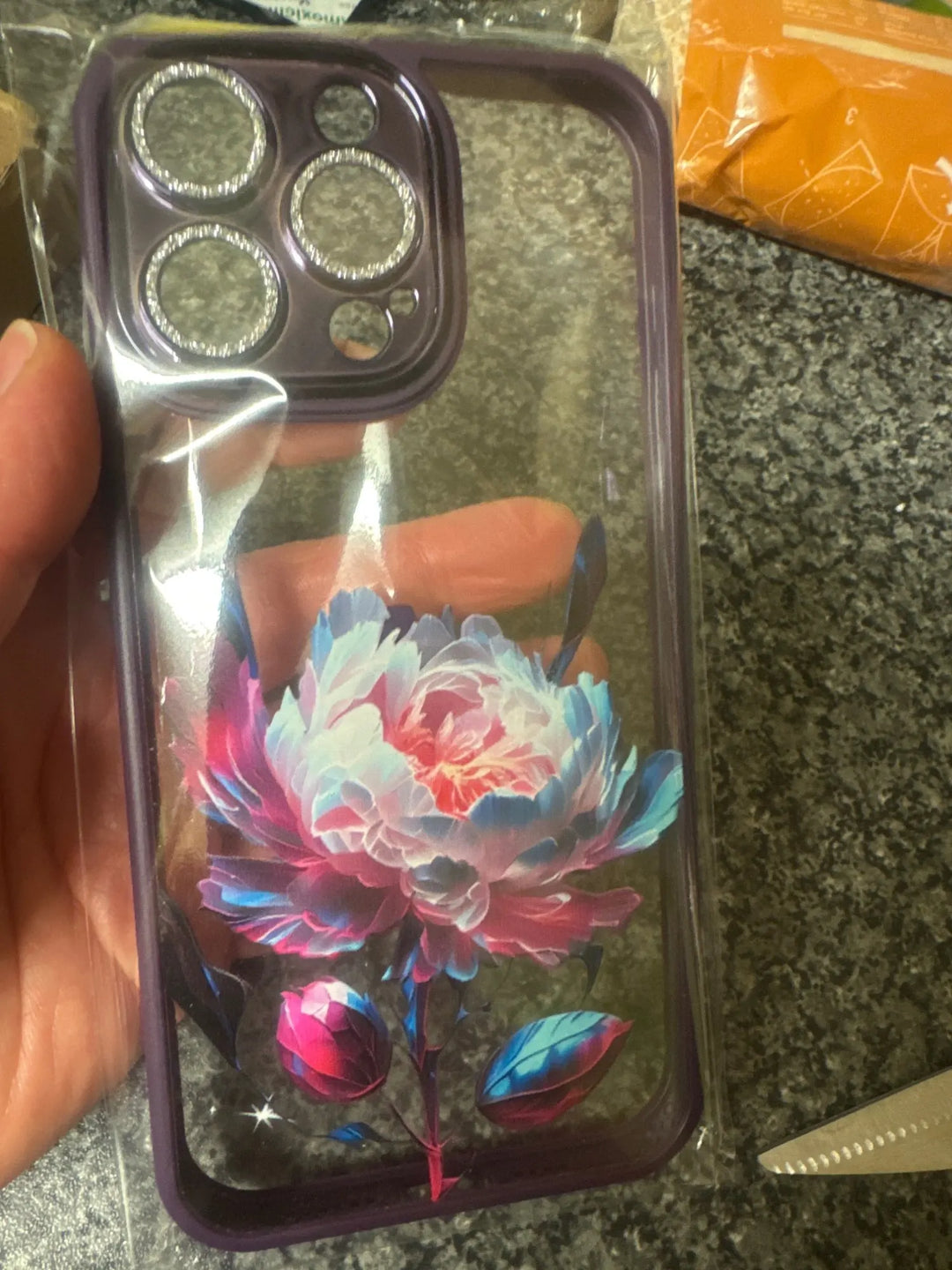 A phone case with a clear, transparent back featuring a vibrant rose design