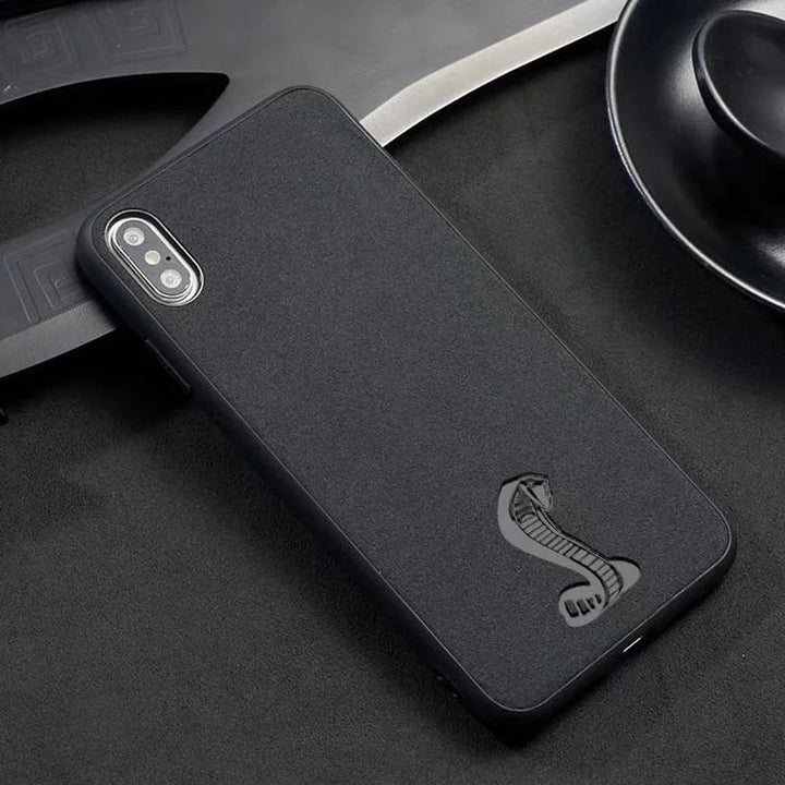 The Shelby for iPhone, a black phone case, showcases an embossed cobra emblem on a textured surface