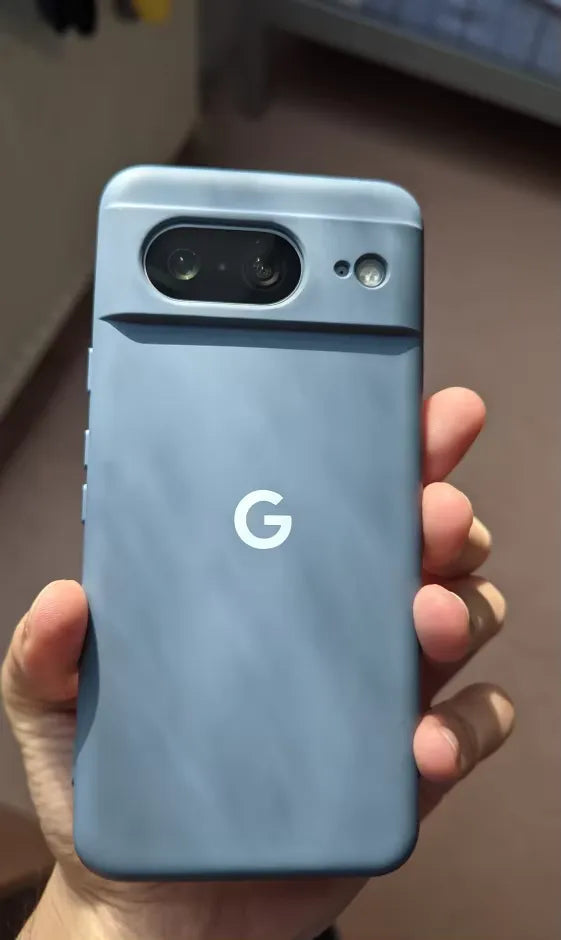 A hand holding a blue Google Pixel smartphone encased in a slim-fit Silicone Case for Google Pixel, showing its rear side with the camera module and Google logo visible.