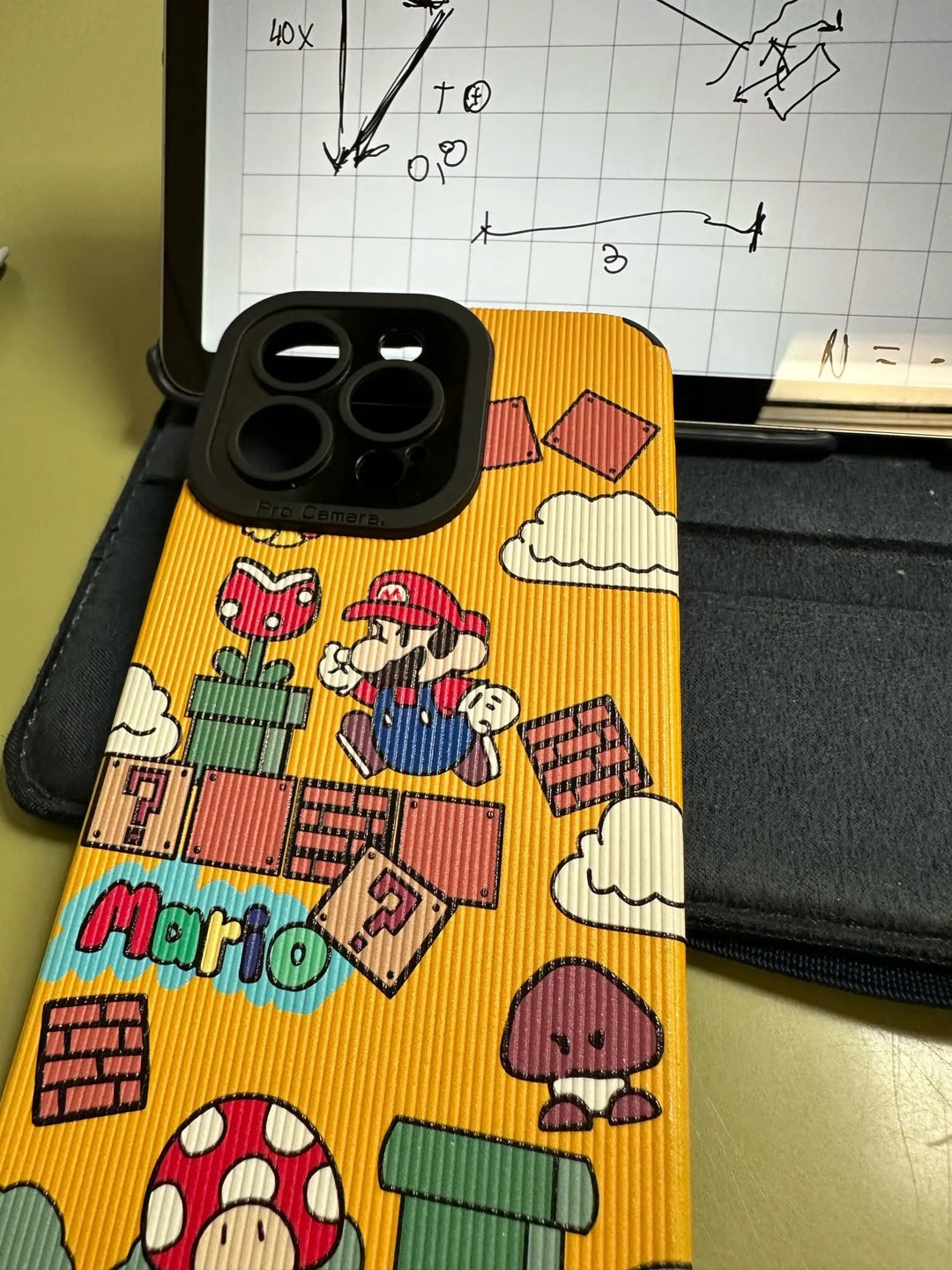 A tablet displaying a math diagram with an iPhone securely placed on top, protected by the Super Mario for iPhone case.