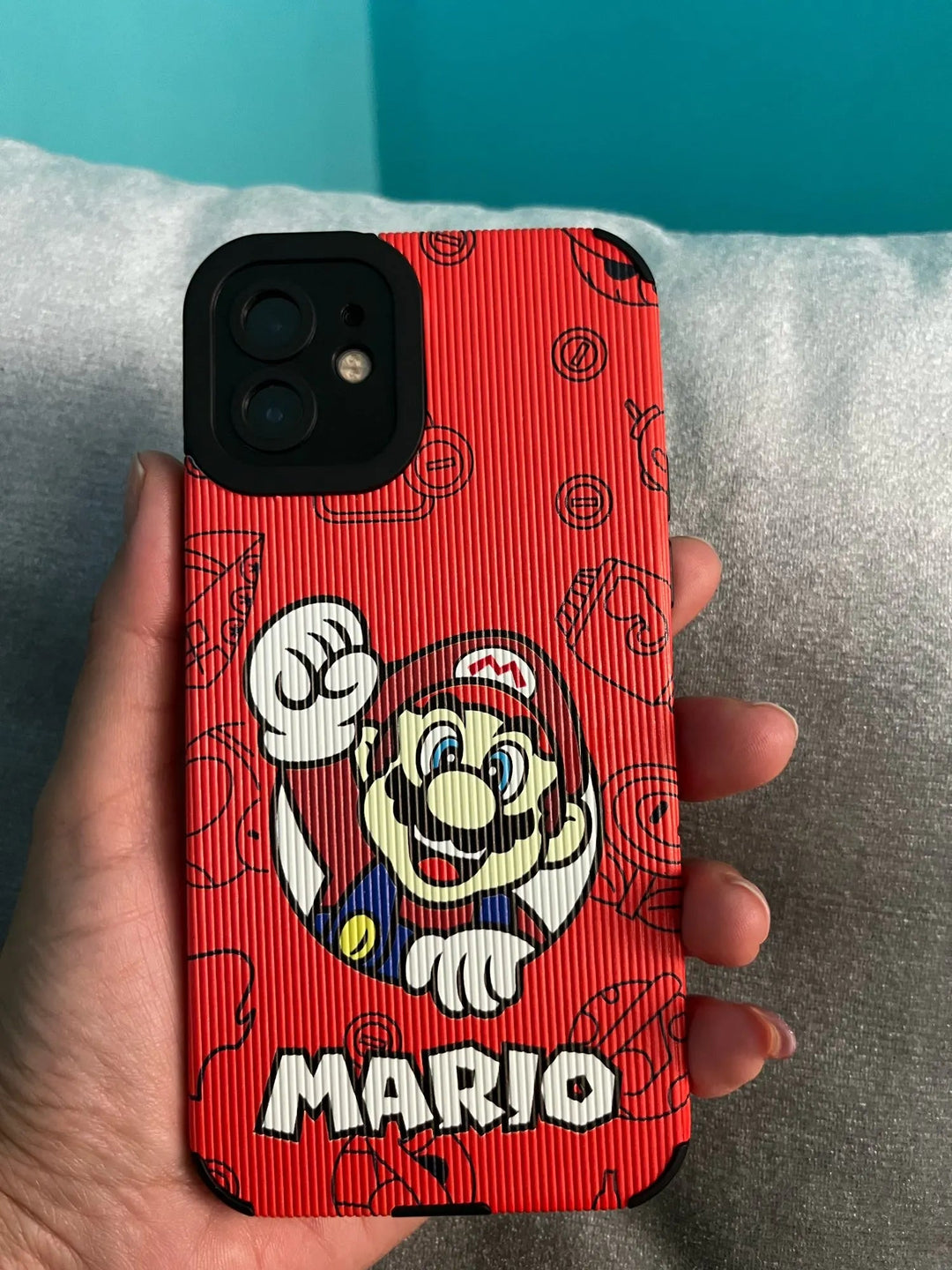 A hand holding a smartphone with the Super Mario for iPhone hard plastic phone case, featuring an eye-catching design. The protective red case showcases the iconic Mario from the beloved video game series.