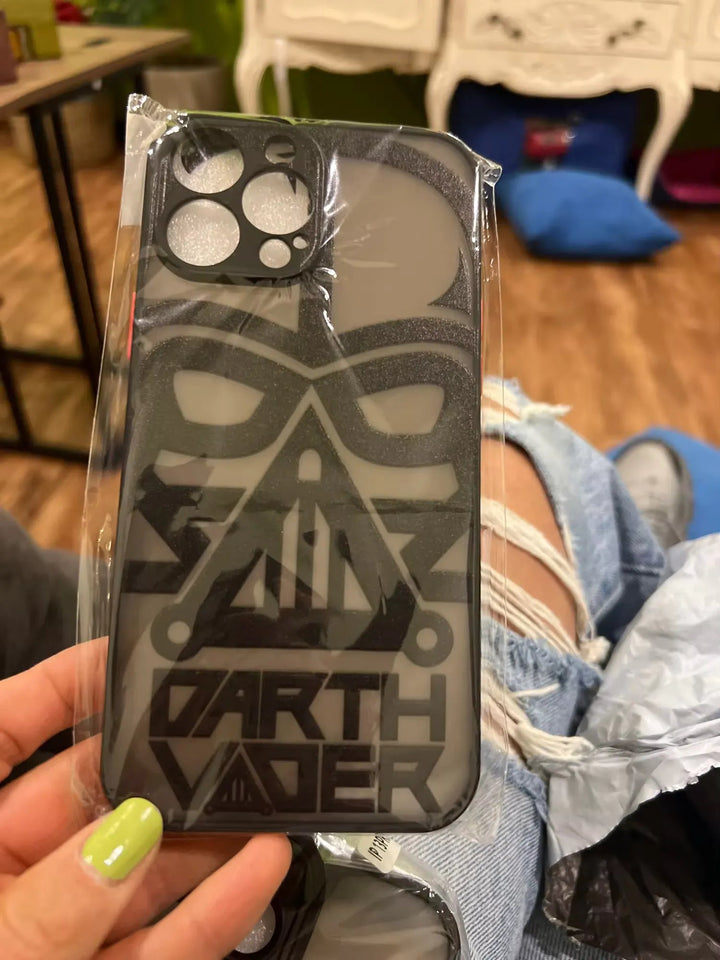 A person holding a packaged Vader Mask for iPhone featuring a black Darth Vader mask design.