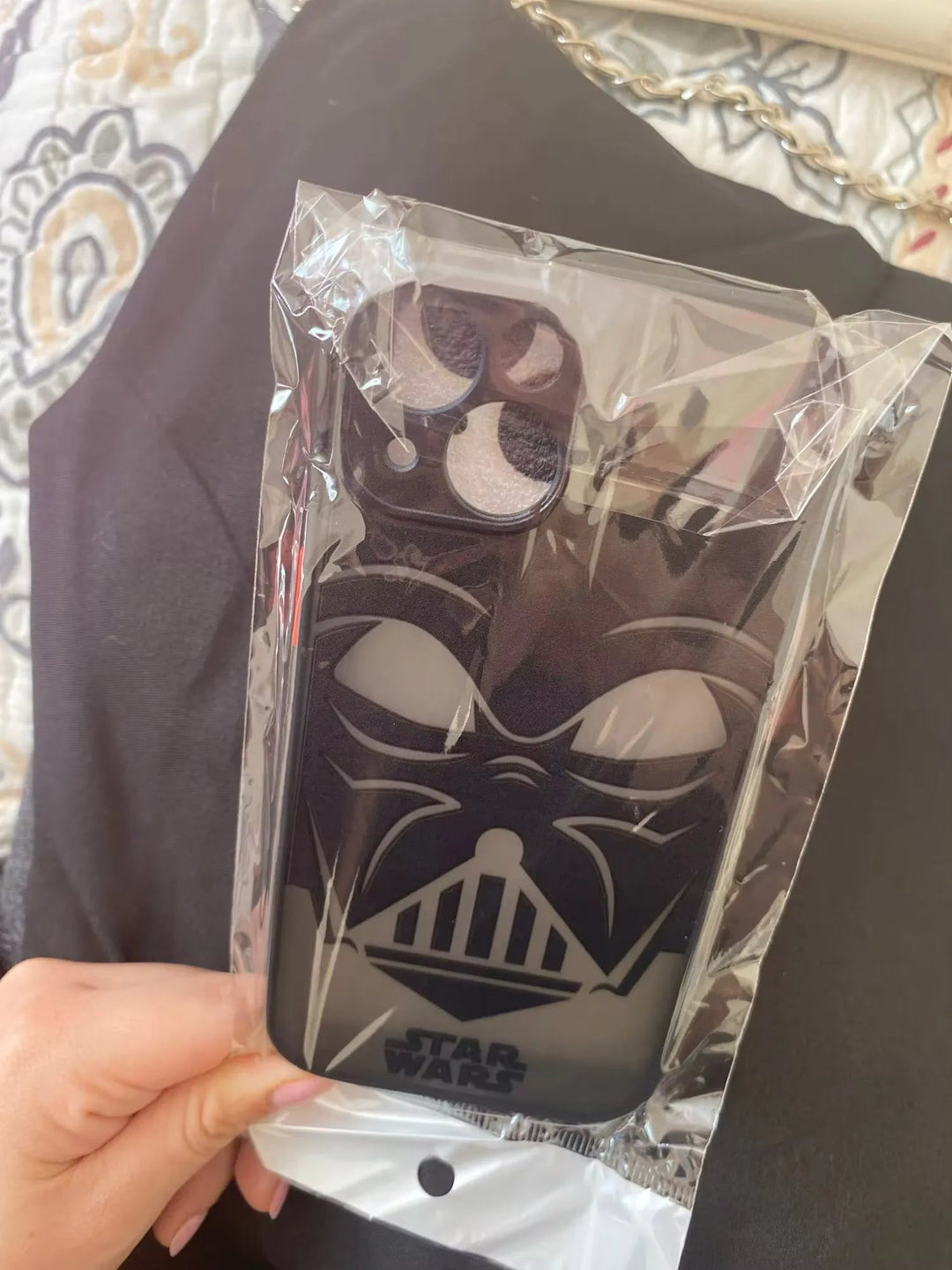 A hand holds a packaged Vader Mask for iPhone featuring a black and white Darth Vader mask design from Star Wars, complete with anti-scratch protection.